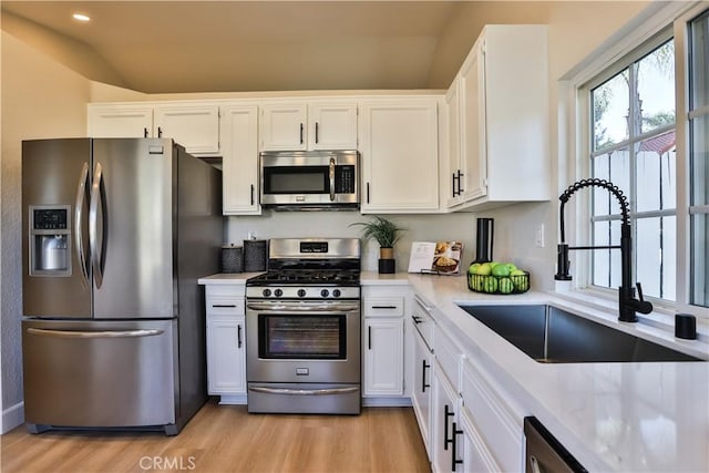 kitchen featuring appliances with stainless steel finishes, light hardwood / wood-style floors, white cabinetry, and sink