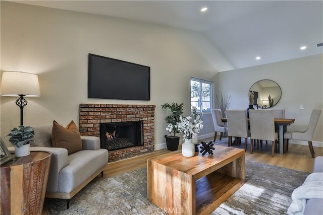 living room featuring lofted ceiling, a fireplace, and hardwood / wood-style floors