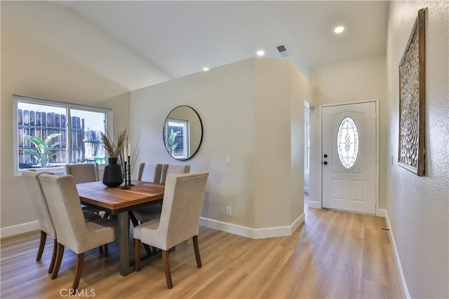 dining area featuring vaulted ceiling and light hardwood / wood-style flooring