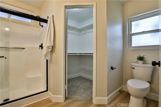 bathroom featuring hardwood / wood-style flooring, toilet, and walk in shower