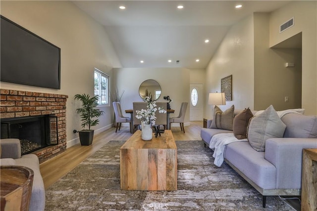 living room with high vaulted ceiling, wood-type flooring, and a fireplace