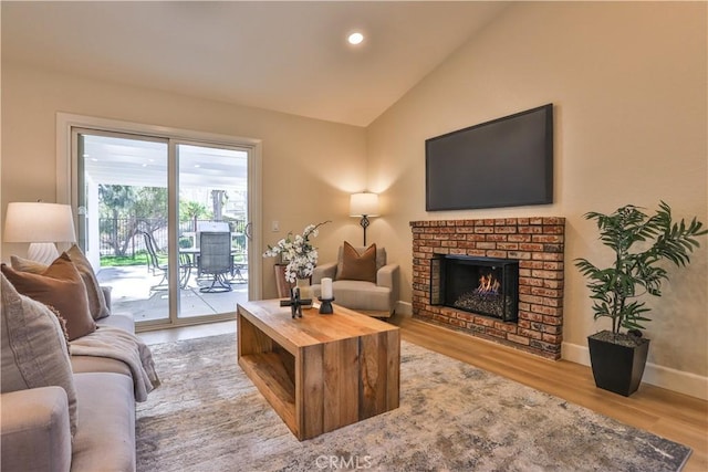 living room featuring vaulted ceiling, light hardwood / wood-style floors, and a fireplace