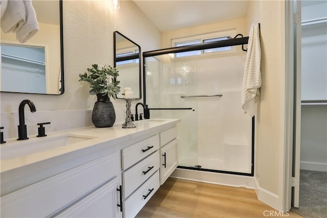 bathroom with a shower with shower door, hardwood / wood-style floors, and vanity