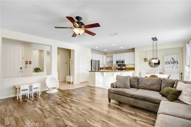 living room with ceiling fan and light hardwood / wood-style flooring