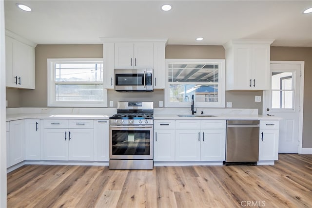 kitchen featuring white cabinets, appliances with stainless steel finishes, sink, and light wood-type flooring