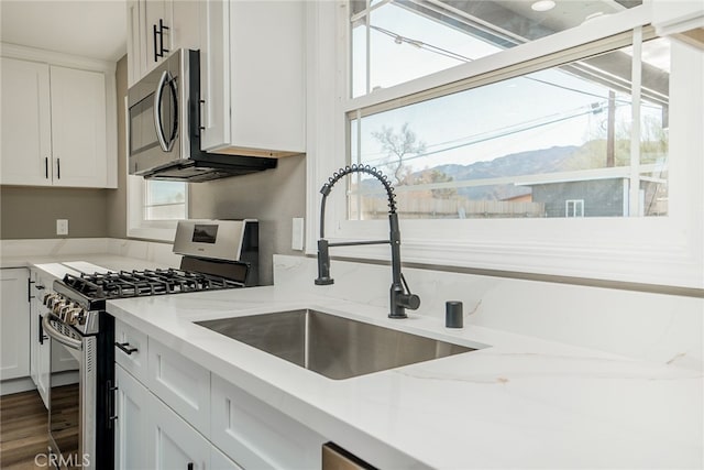 kitchen with stainless steel appliances, a mountain view, white cabinets, and sink