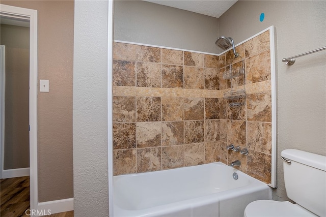 bathroom with toilet and tiled shower / bath