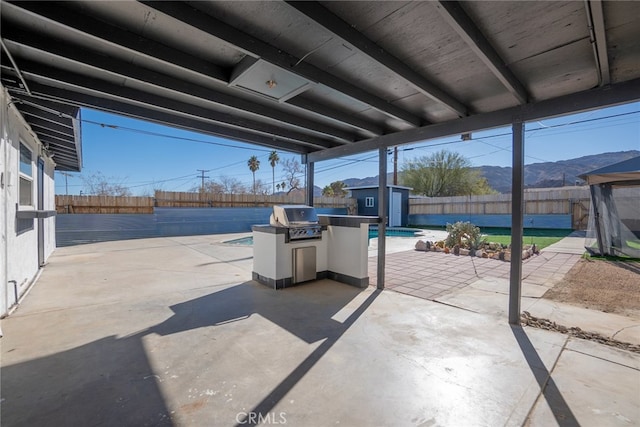 view of patio / terrace with a mountain view, a fenced in pool, a storage shed, and grilling area