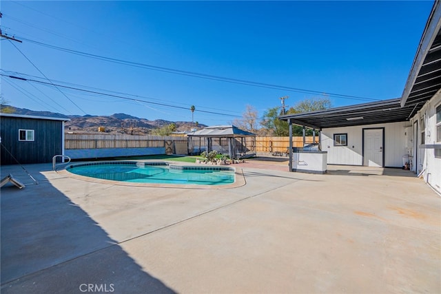 view of swimming pool featuring a mountain view, a shed, a gazebo, and a patio