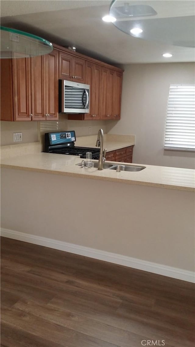 kitchen with a sink, dark wood-type flooring, stainless steel appliances, and light countertops