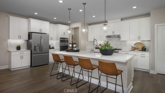 kitchen featuring decorative light fixtures, an island with sink, stainless steel appliances, white cabinets, and dark hardwood / wood-style flooring