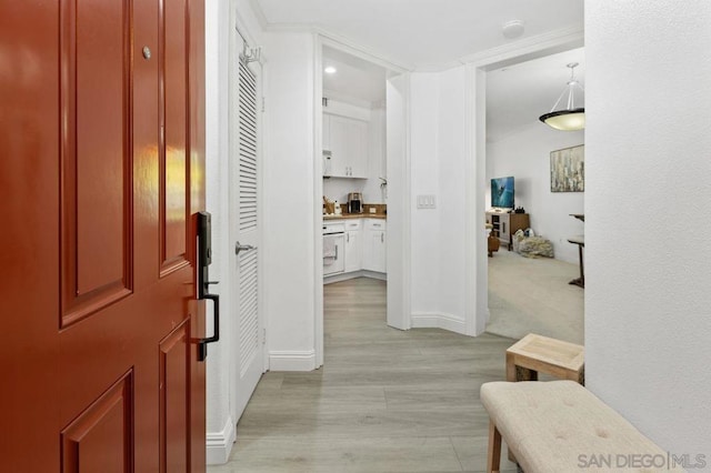 corridor featuring light colored carpet and crown molding