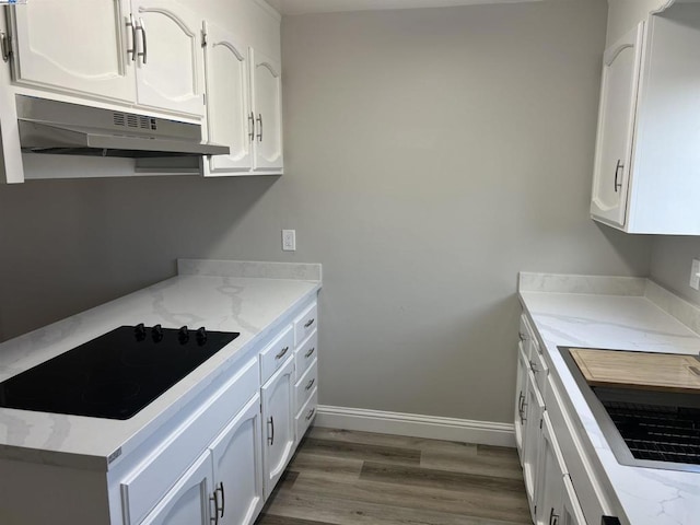 kitchen with black electric stovetop, white cabinets, and light stone countertops