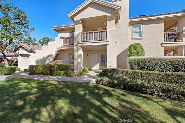 view of front of property with a balcony and a front lawn