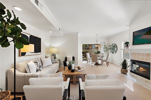 living room featuring carpet floors, a tiled fireplace, and ornamental molding