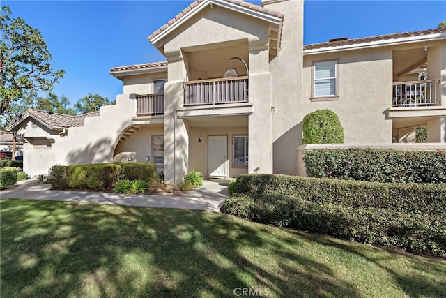 view of front of home with a balcony and a front lawn