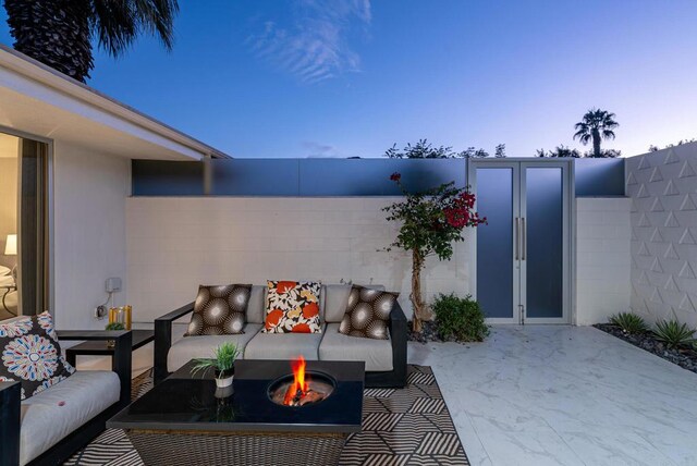 patio terrace at dusk with an outdoor living space with a fire pit