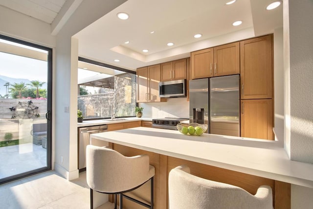 kitchen featuring a kitchen breakfast bar, appliances with stainless steel finishes, kitchen peninsula, and tasteful backsplash