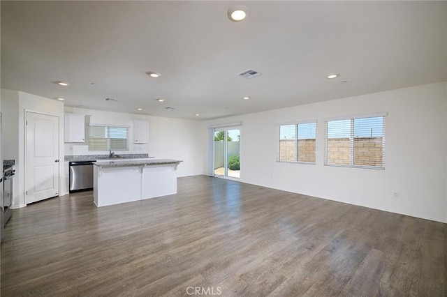 kitchen with a center island, stainless steel dishwasher, sink, white cabinetry, and dark hardwood / wood-style flooring