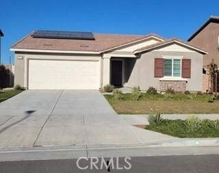 single story home with a garage and solar panels