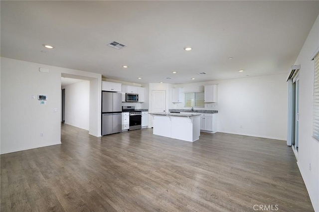 kitchen with white cabinets, dark wood-type flooring, stainless steel appliances, and a kitchen island