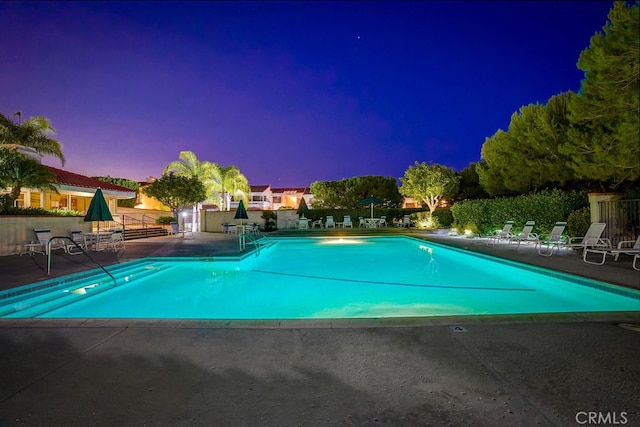 pool at dusk featuring a patio