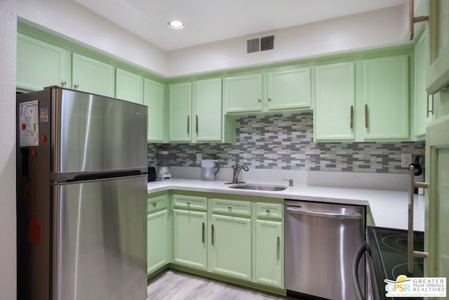 kitchen featuring tasteful backsplash, sink, appliances with stainless steel finishes, and light hardwood / wood-style flooring