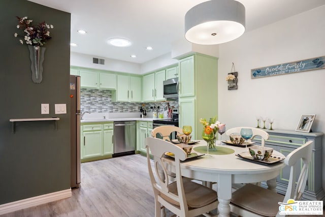 kitchen with backsplash, light hardwood / wood-style flooring, green cabinetry, and appliances with stainless steel finishes