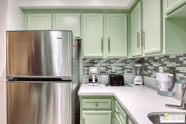 kitchen with stainless steel fridge, tasteful backsplash, and green cabinetry