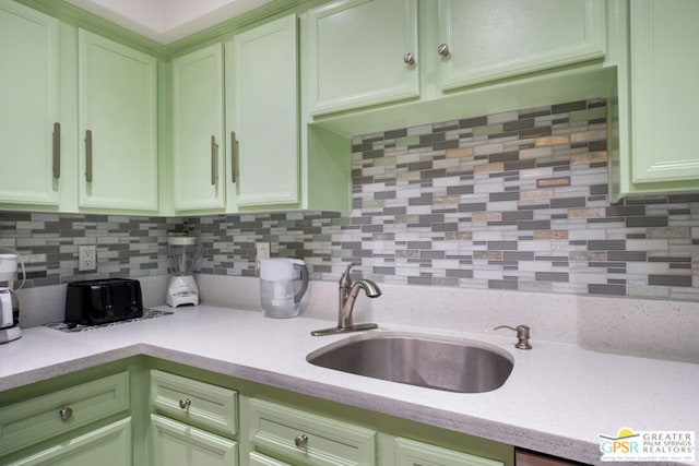 kitchen featuring green cabinetry, sink, and tasteful backsplash