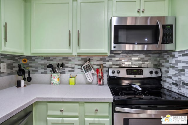 kitchen featuring backsplash, green cabinets, and appliances with stainless steel finishes