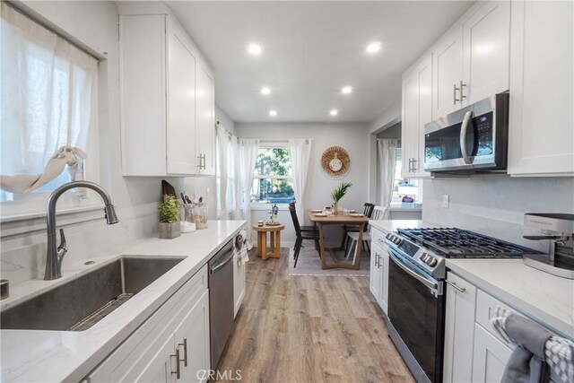 kitchen with stainless steel appliances, white cabinetry, and sink