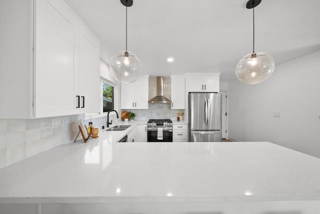 kitchen featuring white cabinets, pendant lighting, appliances with stainless steel finishes, and wall chimney exhaust hood