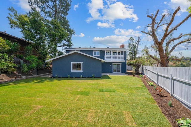 rear view of property with a balcony and a yard