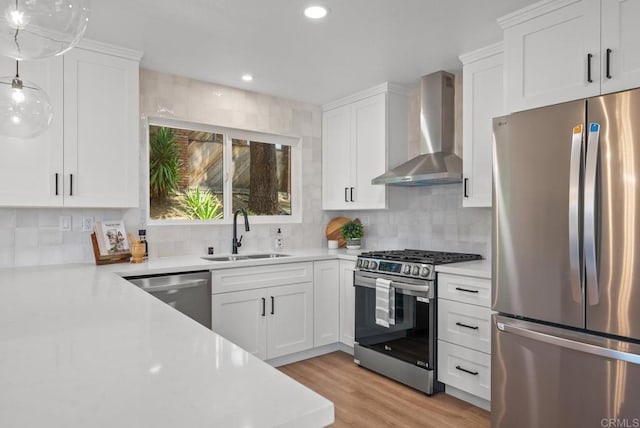 kitchen with white cabinetry, appliances with stainless steel finishes, tasteful backsplash, wall chimney exhaust hood, and sink