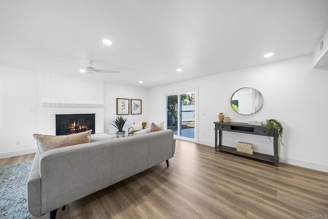 living room with ceiling fan, hardwood / wood-style flooring, and a fireplace