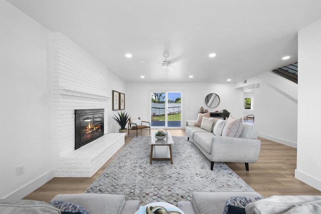 living room with ceiling fan, a fireplace, and hardwood / wood-style floors