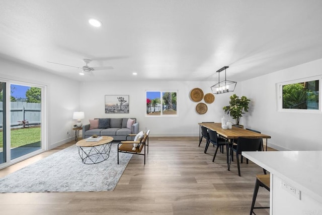 living room featuring ceiling fan with notable chandelier and light hardwood / wood-style floors