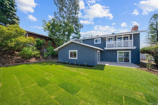 back of property with a balcony, a yard, and a patio