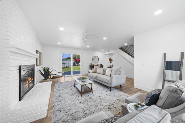 living room featuring ceiling fan, a fireplace, and light hardwood / wood-style flooring