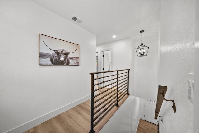 stairway featuring wood-type flooring and a notable chandelier