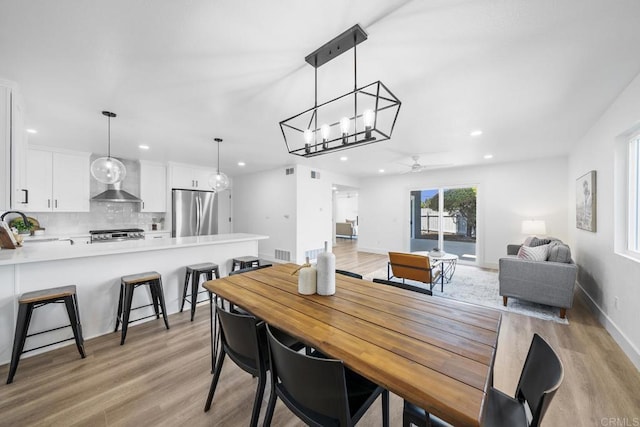 dining room with ceiling fan, sink, and light wood-type flooring