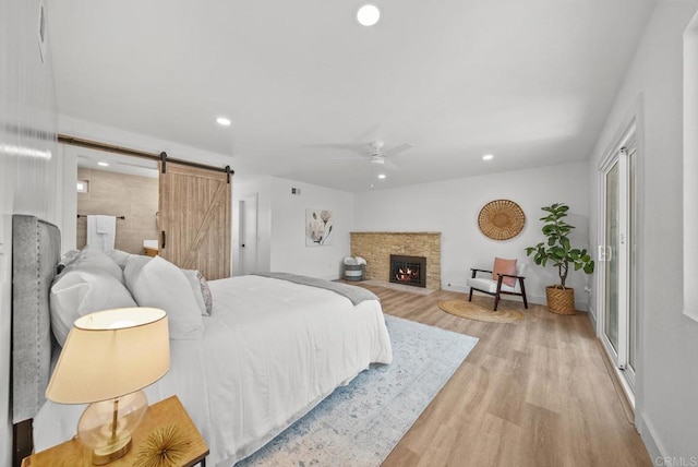 bedroom with ceiling fan, a barn door, and light hardwood / wood-style floors