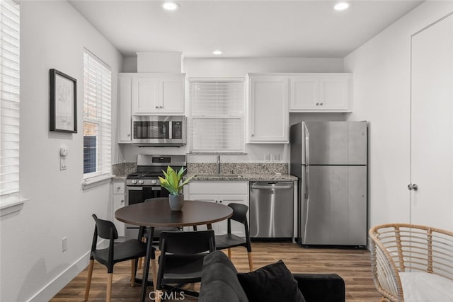 kitchen with white cabinets, light stone countertops, sink, and stainless steel appliances