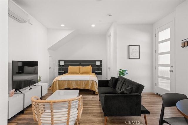 bedroom with a wall mounted AC and wood-type flooring