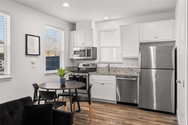 kitchen featuring sink, dark wood-type flooring, light stone countertops, appliances with stainless steel finishes, and white cabinets