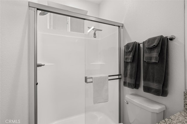 bathroom featuring toilet and a shower with door