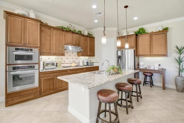 kitchen with sink, ornamental molding, stainless steel appliances, light stone countertops, and a kitchen island with sink