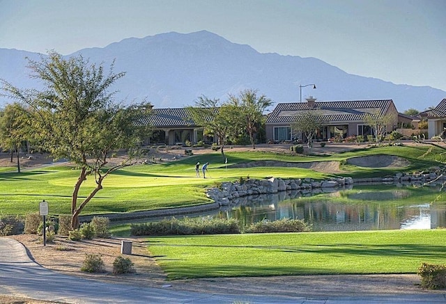 view of property's community with a water and mountain view and a yard