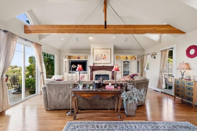 living room with vaulted ceiling with beams and light wood-type flooring